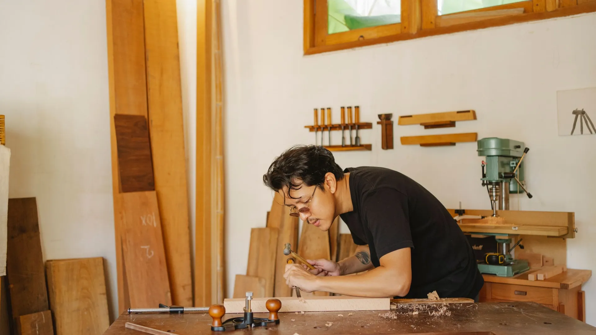 Thợ mộc chế tác bên bàn gỗ trong xưởng sáng